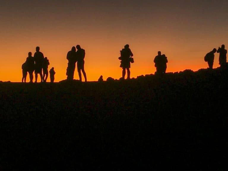 Visitors silhouetted against the sunrise glow at the Haleakala summit