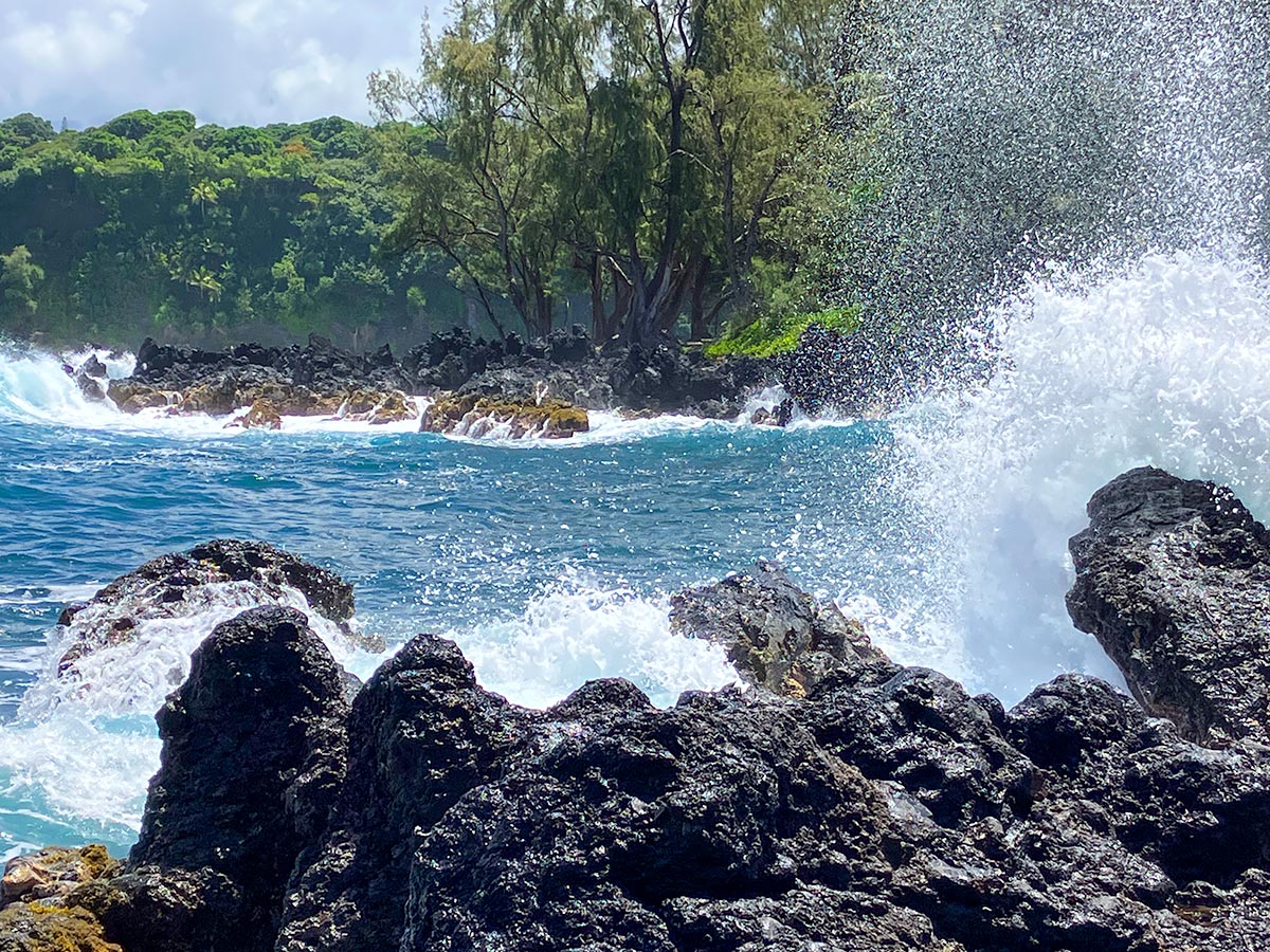 Waves crashing over black lava rock on the Hana coast