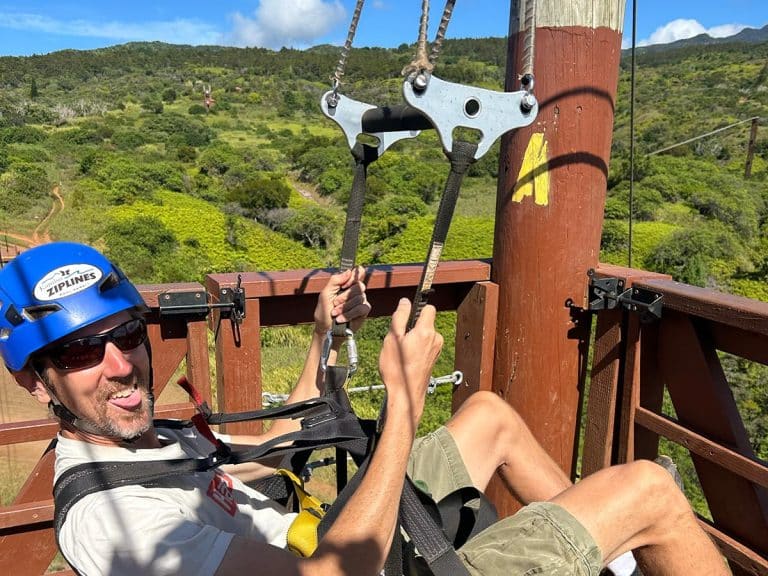 A zipliner in a Kapalua Ziplines helmet about to launch from a platform in the West Maui Mountains
