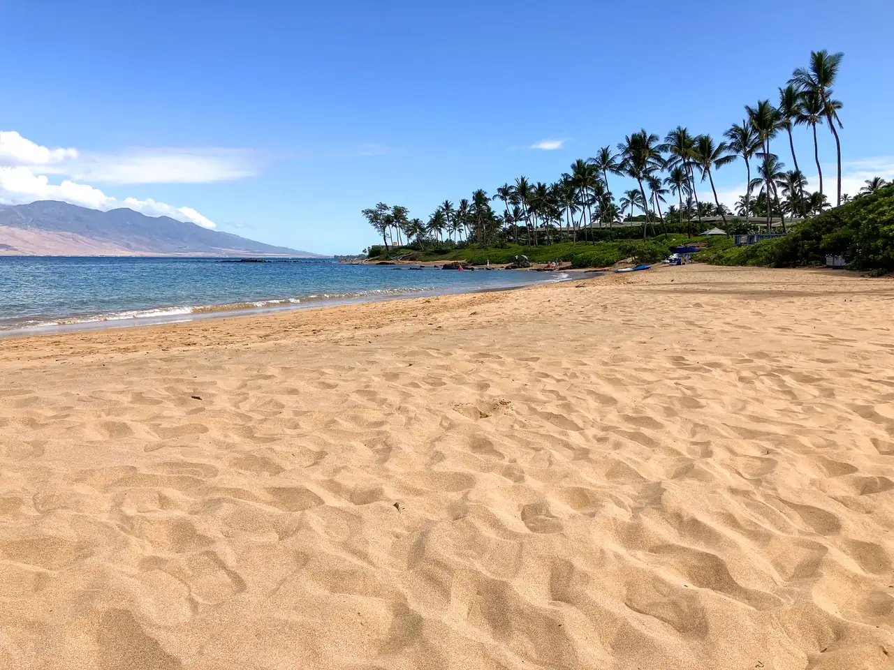 Empty golden sand at Mokapu Beach in Wailea, Maui, under a clear blue sky