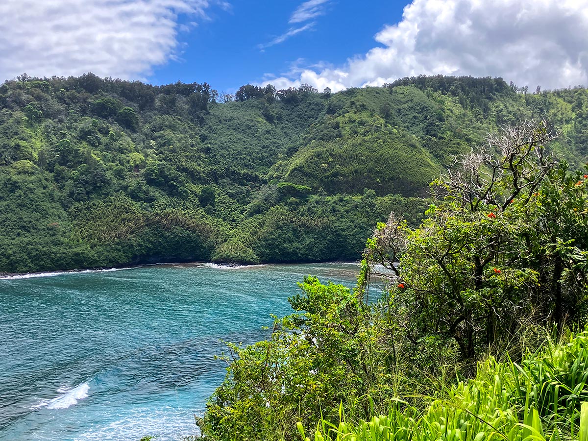 Turquoise bay below green cliffs along the Road to Hana