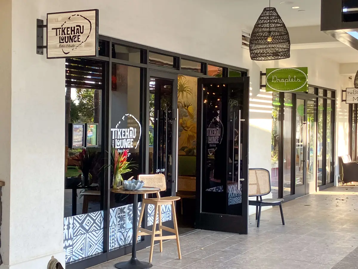 Entrance to Tikehau Lounge at Wailea Village, with its sign and a small patio table