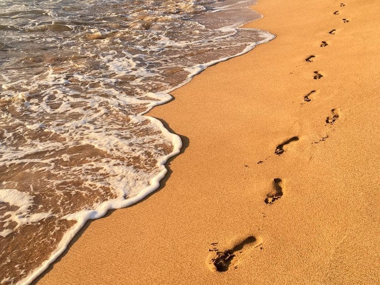 Footprints in golden sand along the shoreline at a Wailea beach on Maui